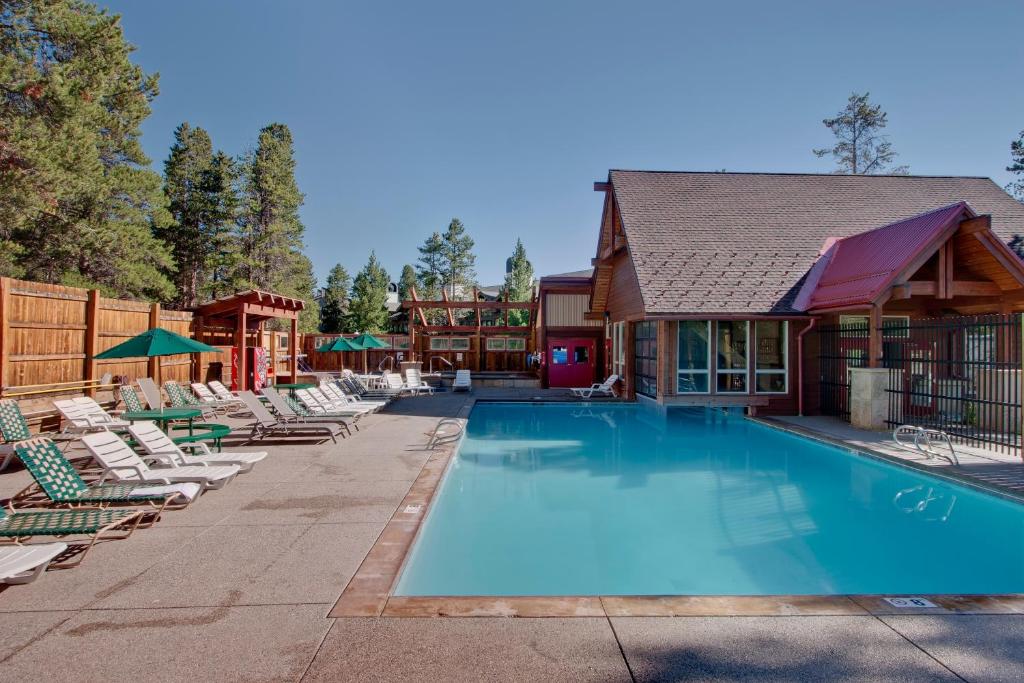 a swimming pool with lounge chairs and a house at Pine Ridge Condos in Breckenridge