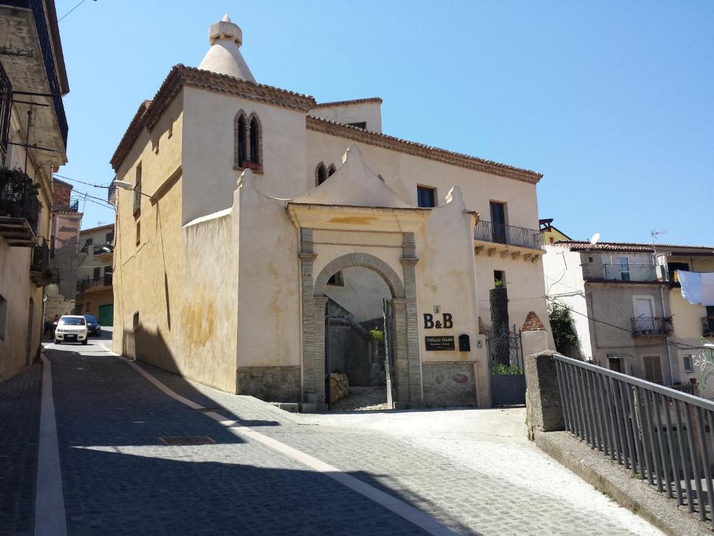 an old building with an arch in a street at Palazzo Madeo - Residenza d'Epoca in Crosia