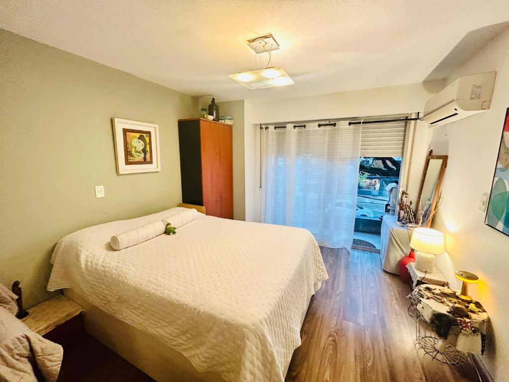Un dormitorio con una cama blanca y una ventana. en lindo apartamento en pocitos con balcon, en San Gregorio de Polanco