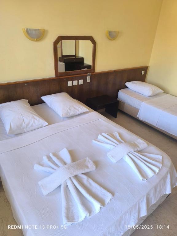 two beds in a hotel room with towels on them at Sun Shine Mir Otel in Eskiömerler