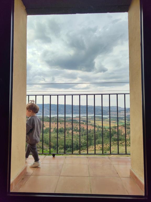 a little boy standing in a room looking at the view from a balcony at Casa Rural María in Los Alagones