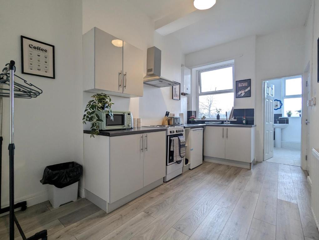 a kitchen with white cabinets and a wooden floor at Modern Apartment Near Manchester City Centre in Manchester