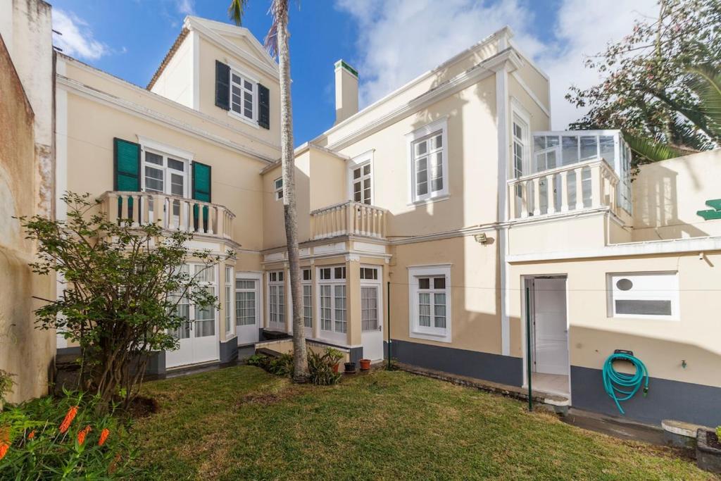 an exterior view of a large white house with a yard at Casa da Rua D'água in Ponta Delgada