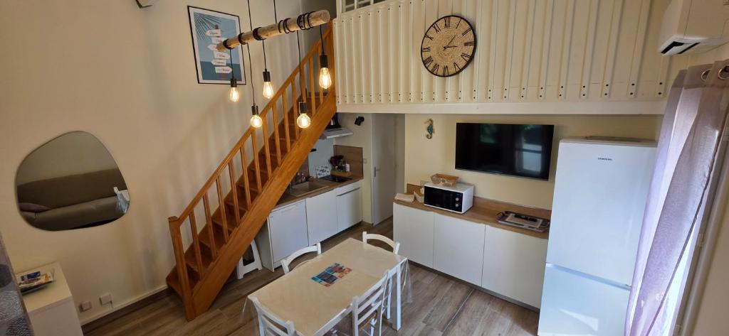 un salon avec un escalier et une horloge sur le mur dans l'établissement Villa Canto Rano, à Valras-Plage