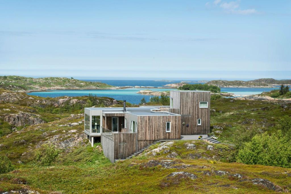 a house on a hill with the ocean in the background at Vestavindshagen - Modern Gem By Sea And Hills in Leirvåg