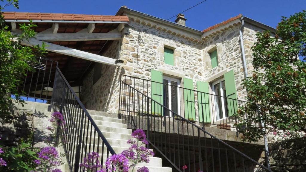 une ancienne maison en pierre avec des escaliers et des fleurs dans l'établissement Maison de caractère en pierre, à Laurac-en-Vivarais