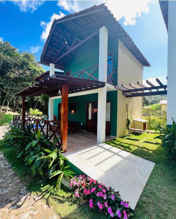 a house with a patio and flowers in the yard at Chalé Sossego Serrano in Mulungu