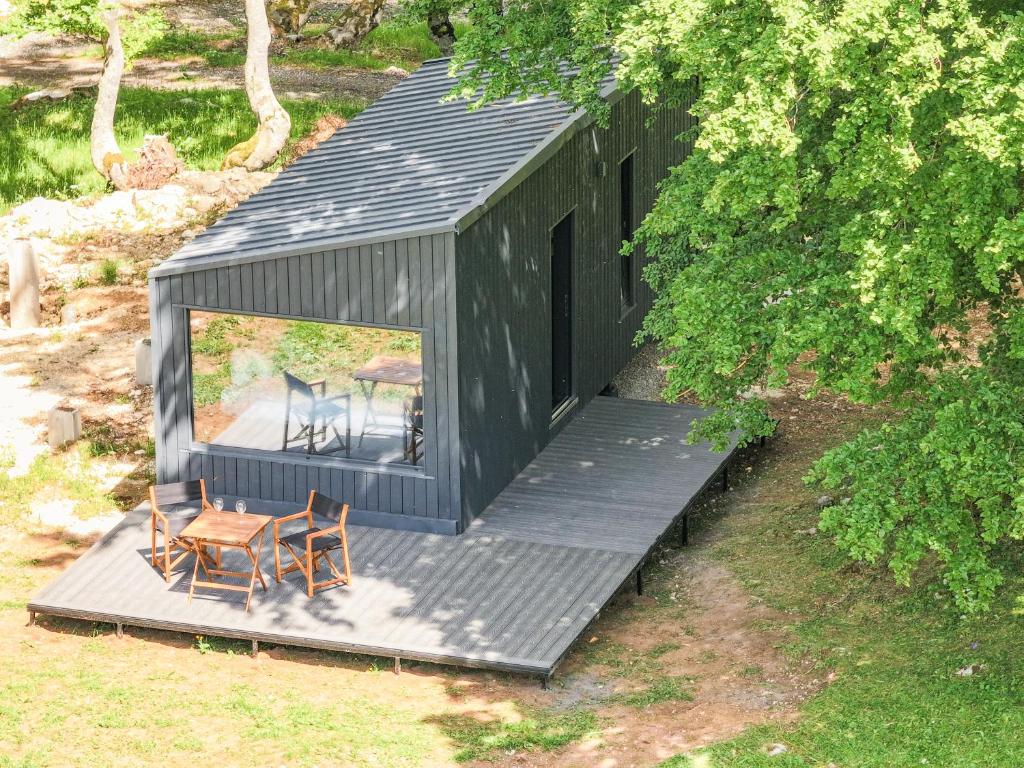 a black house with a table and chairs on a deck at Ginger Cabins in Žabljak