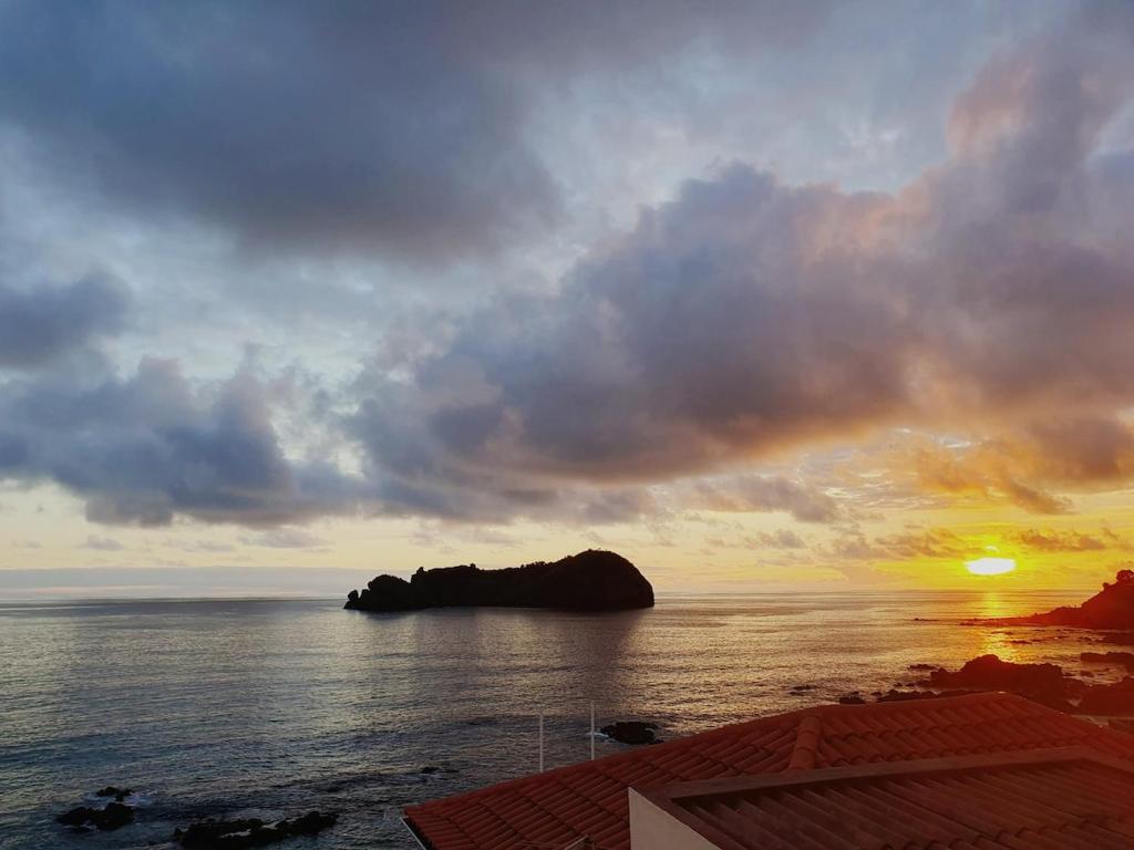 a sunset over the ocean with a rock in the water at Vila do Ilhéu in Vila Franca do Campo