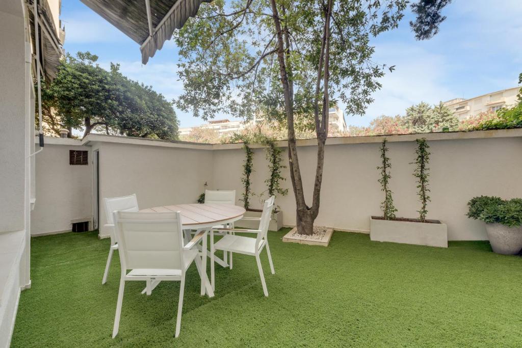 une table et des chaises sur une terrasse avec de l'herbe verte dans l'établissement Modern 2 chambres avec jardin Martinez , 5 minutes from palais of festivals, à Cannes