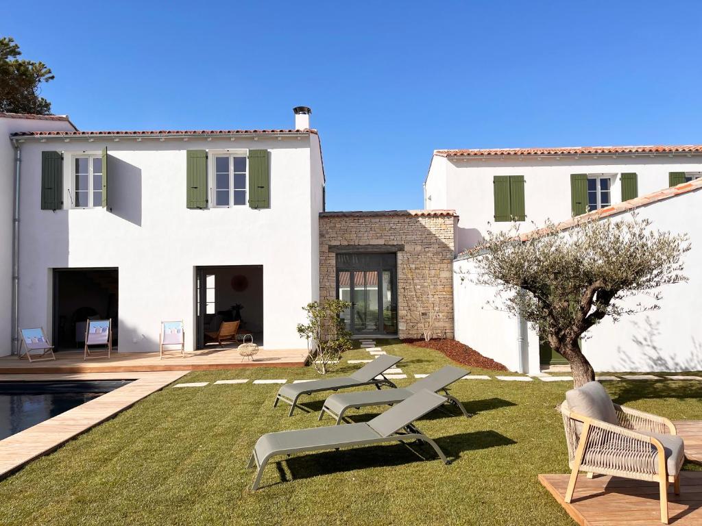 une villa avec une cour avec des chaises et une piscine dans l'établissement Somptueuse villa 9 chambres et sa piscine privé - 100 m de la plage, à La Couarde-sur-Mer