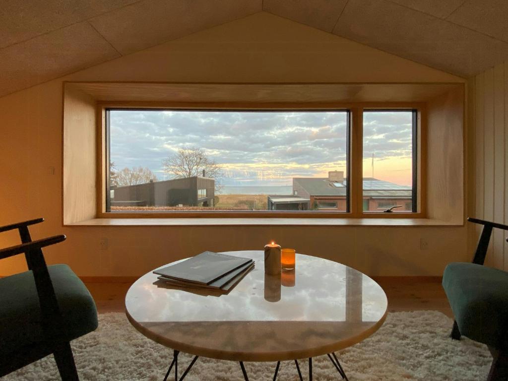 オルダーにあるRenovated Wooden House Near Saksild Beachのテーブルと大きな窓のあるリビングルーム