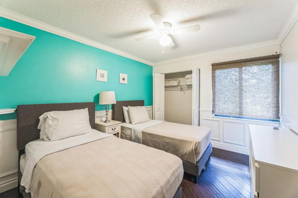 a bedroom with two beds and a blue wall at NEW Pool Home with King Bed Mins to Hospital and Beach in Fort Lauderdale