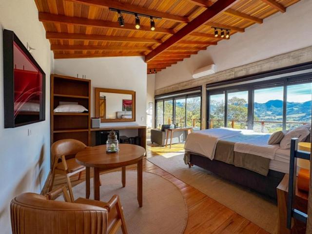 a bedroom with a bed and a desk and a table at Chalé - Vila Bertina in Gonçalves