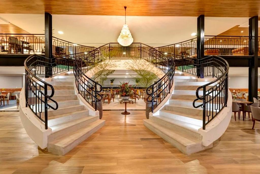 una escalera en un edificio con mesas y sillas en Campos do Jordão - Gran Paradiso Resort, en Campos do Jordão