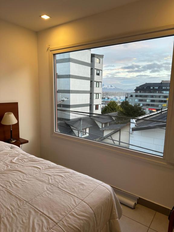 een slaapkamer met een groot raam met uitzicht op een gebouw bij Antártida Argentina 63 in Ushuaia