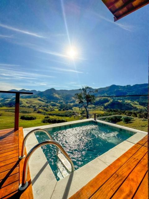 a swimming pool with a chair next to a wooden deck at Chalé - Vila Bertina in Gonçalves