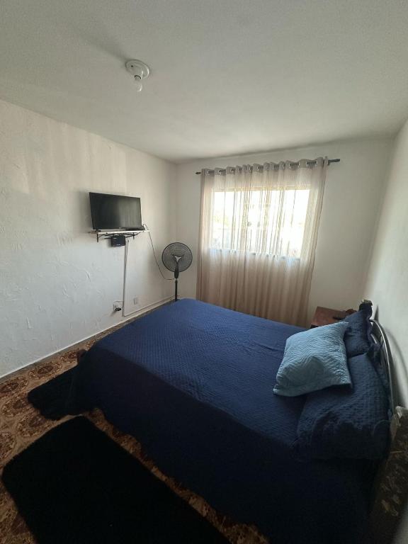 a bedroom with a blue bed and a television at Suíte no centro in Saquarema