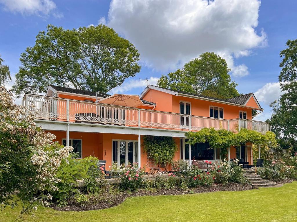 an orange house with a balcony and a yard at Dunburgh Wood in Beccles