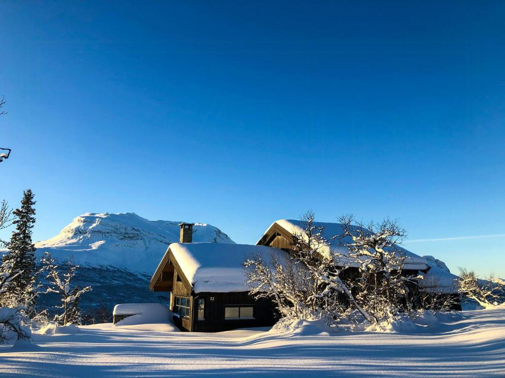 a house covered in snow with a mountain in the background at Cozy Holiday Home Embraced By Valdres Hills in Vang I Valdres