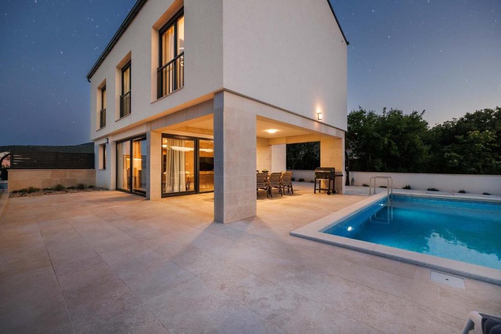 ein Haus mit einem Swimmingpool davor in der Unterkunft Holiday house with a swimming pool Vrbnik, Krk - 24526 in Vrbnik