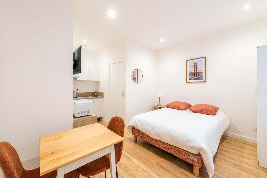 une chambre avec un lit, une table et des chaises dans l'établissement Studio lumineux et confortable Proche Douai Centre, à Douai