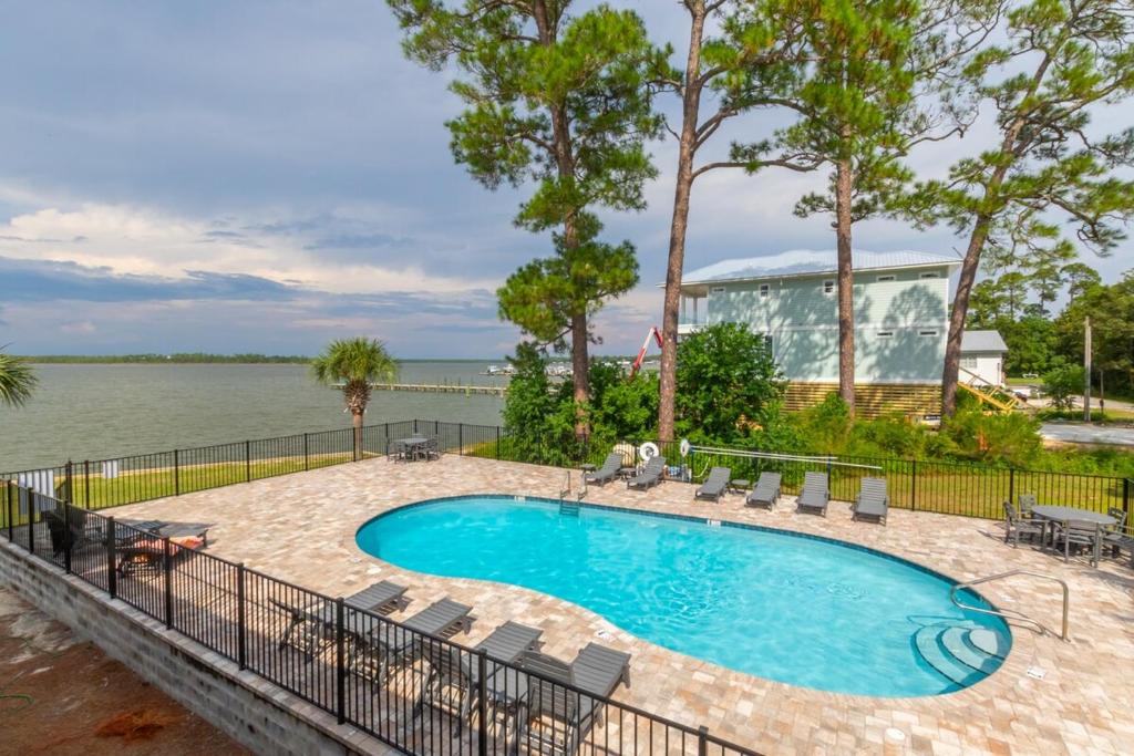 a swimming pool with chairs and the water at Wolf Bay Villas in Orange Beach