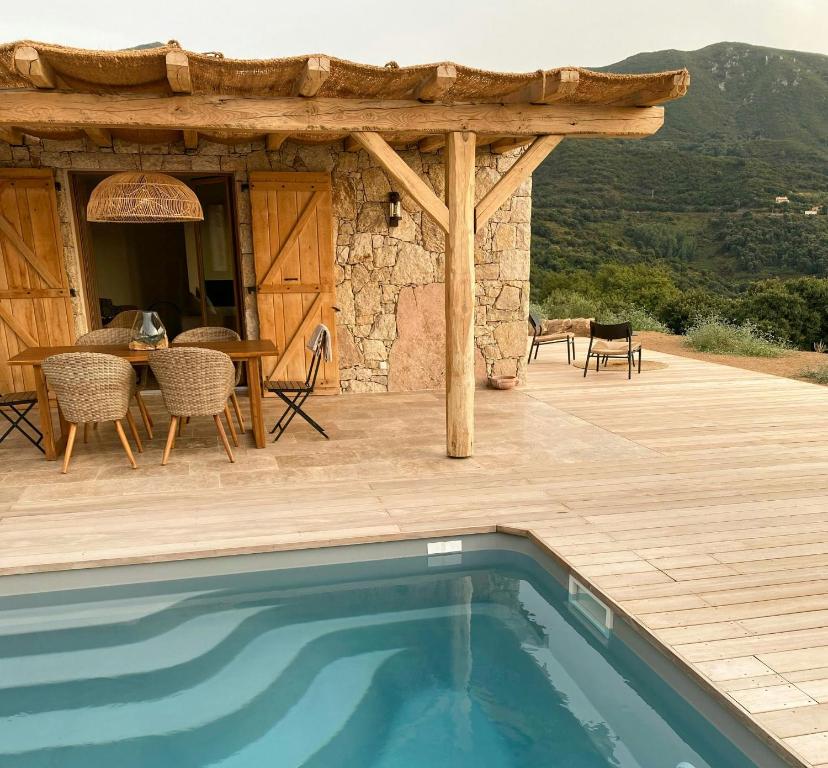 une maison avec une piscine sur une terrasse en bois dans l'établissement Stone Sheepfold With Sea View In Corsica, à Sari-dʼOrcino
