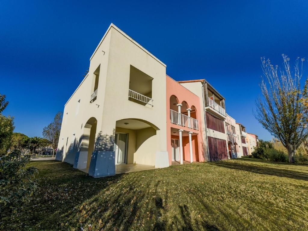 un grand bâtiment blanc sur une pelouse dans l'établissement Apartment in Catalana with Balcony, au Barcarès