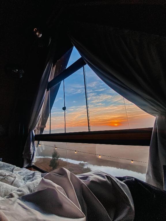 a bedroom with a window looking out at a sunset at Cabanas Arroio Da Serra in Cambará