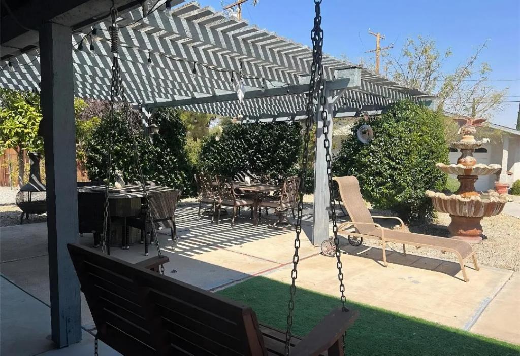 a swing in a patio with a table and a fountain at Quaint Little Studio in Apple Valley