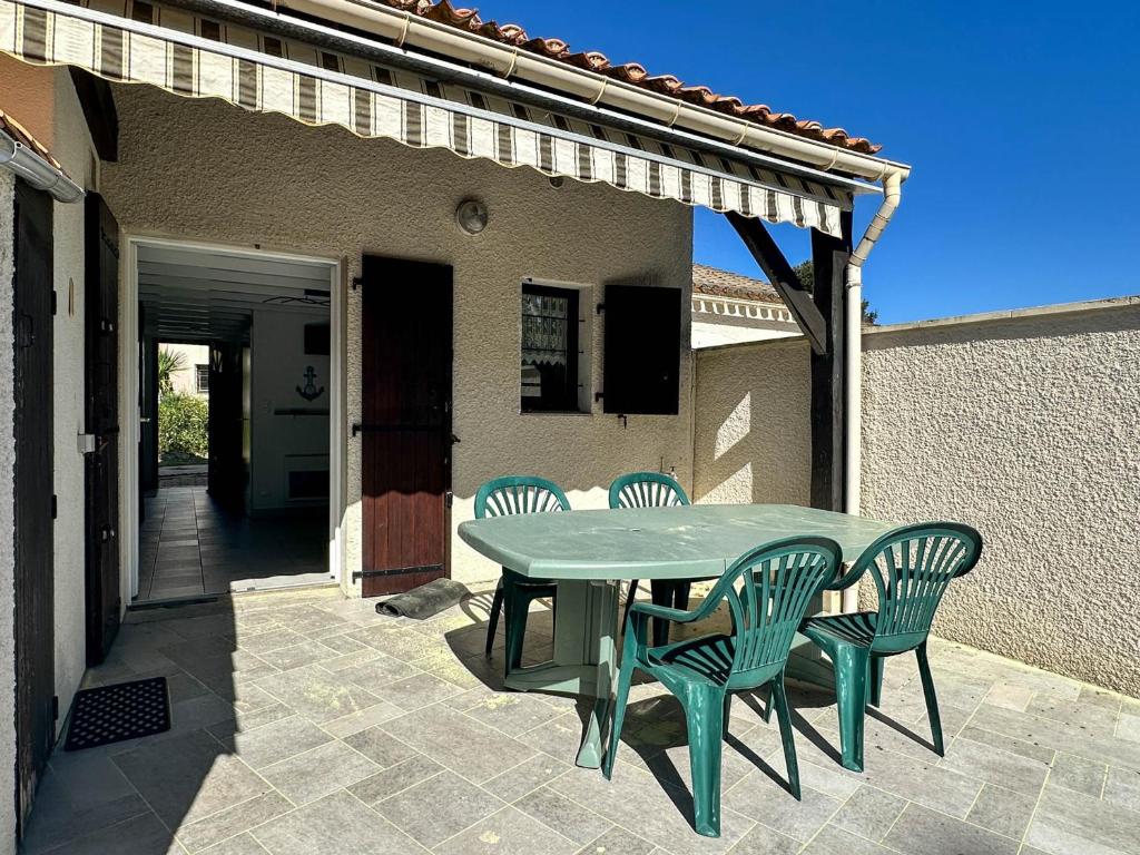 une table et des chaises vertes sur la terrasse dans l'établissement Maison plage à 900m, 3 chambres, terrasse, barbecue, parking, proximité commerces, calme assuré - FR-1-705-61, aux Mathes