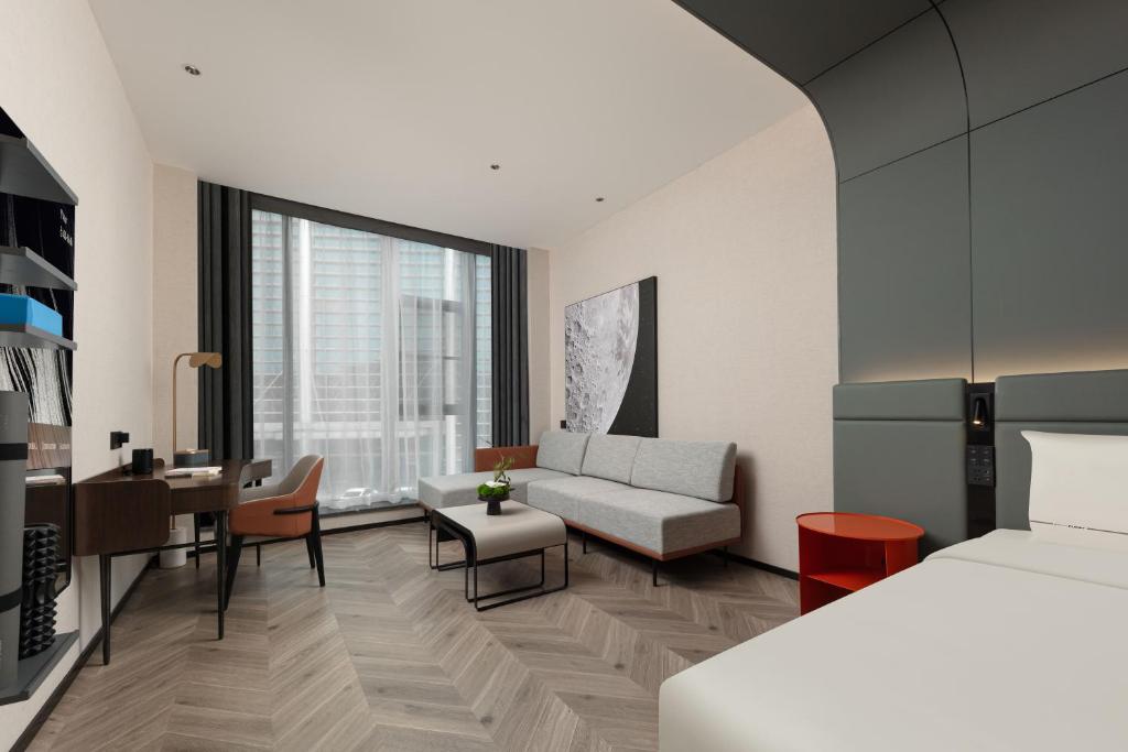 Atour S Hotel Suzhou Jinji Lake Moonlight Pier في سوتشو: غرفة نوم مع سرير وغرفة معيشة