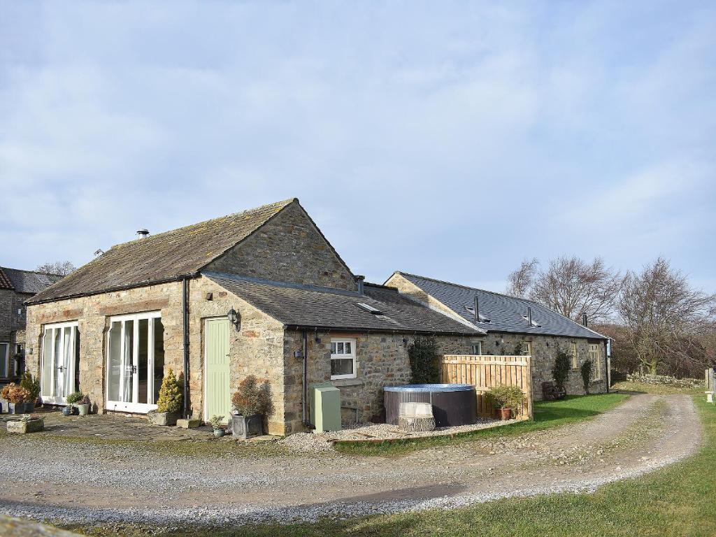 an old stone house with a driveway in front of it at High Dalton Hall Cottage in Newsham