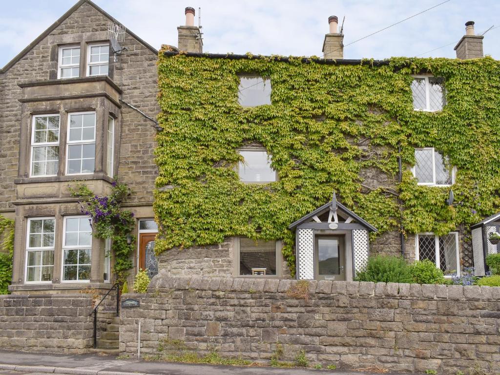 an ivy covered house with a stone wall at Easter Cottage in Bamford