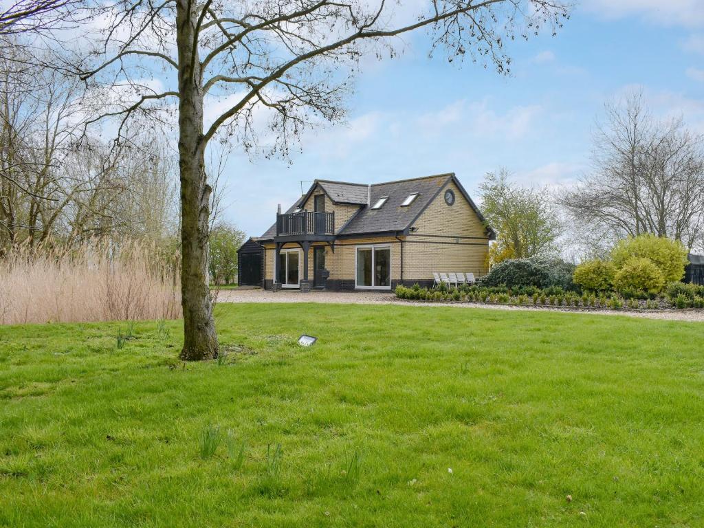 a house with a tree in a field at Hill Farm Cottage in Stretham