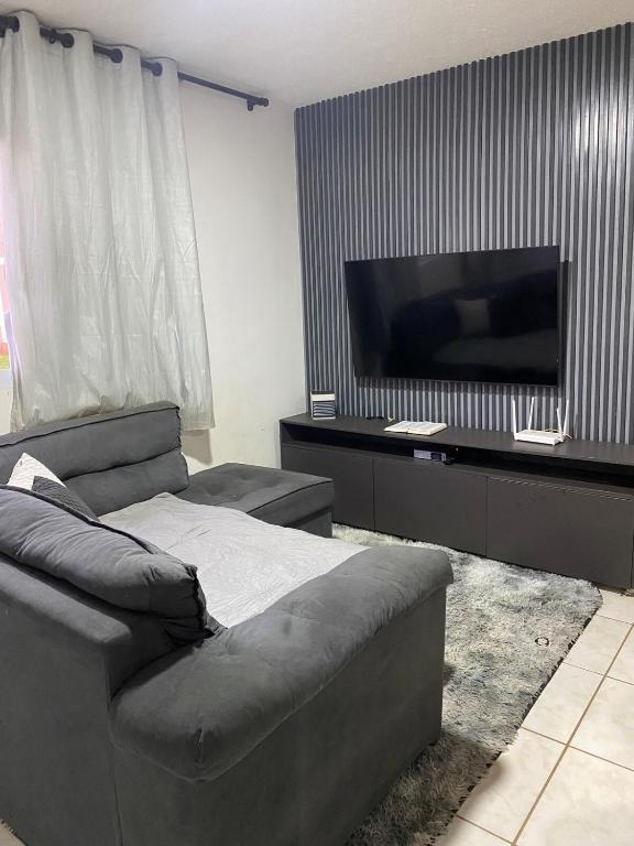 a living room with a couch and a flat screen tv at Apto Completo com Cozinha Equipada in Valparaíso de Goiás