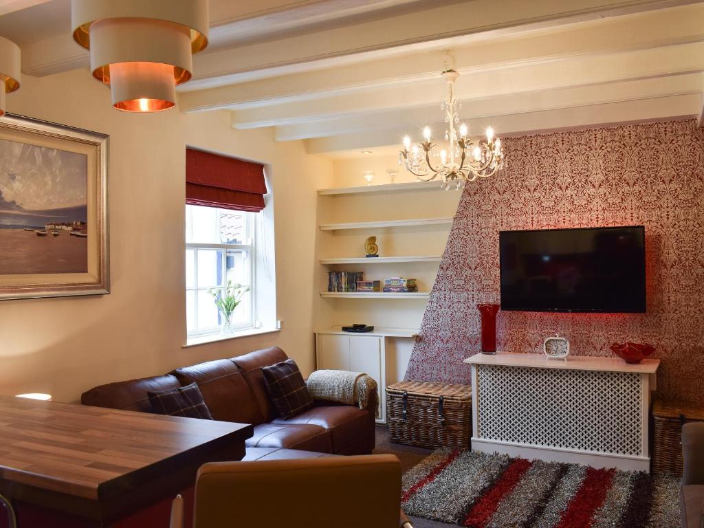 Una sala de estar con un sofá y un televisor. en Honeyz Hideaway, en Whitby