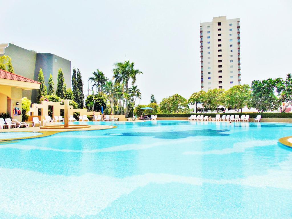 a large swimming pool with chairs and a building at Sea View Beachfront Condos Pattaya Jomtien Beach in Jomtien Beach