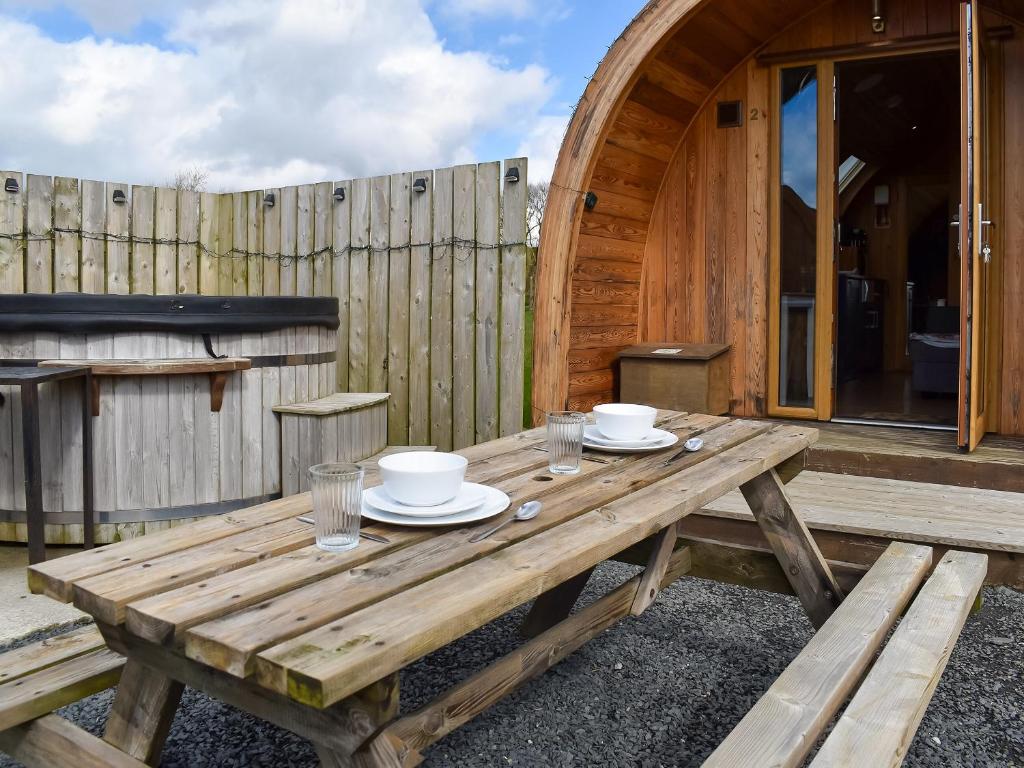 a wooden picnic table with two cups and plates on it at Withy Bottom-Uk1393 in Corney