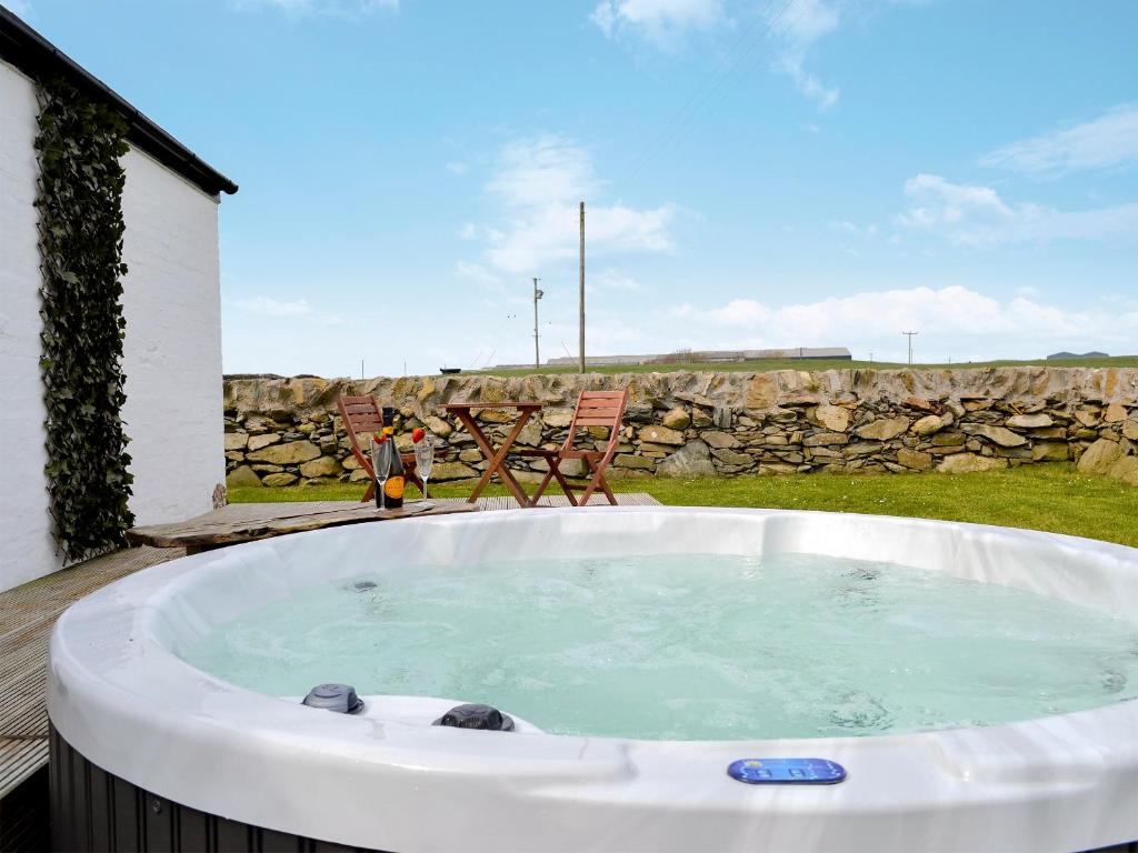 un jacuzzi dans une cour avec un mur en pierre dans l'établissement Cotters Cottage - Uk10922, à Whithorn