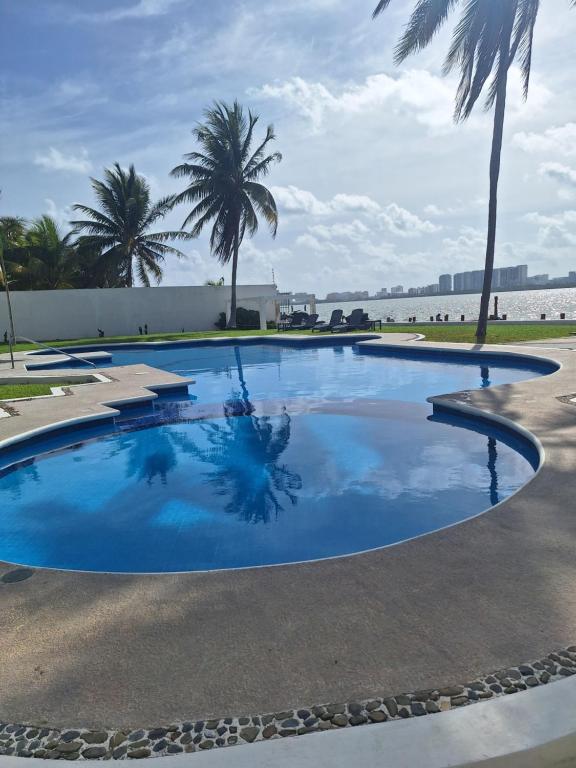 a large blue swimming pool with palm trees in the background at Condo Azul in Cancún