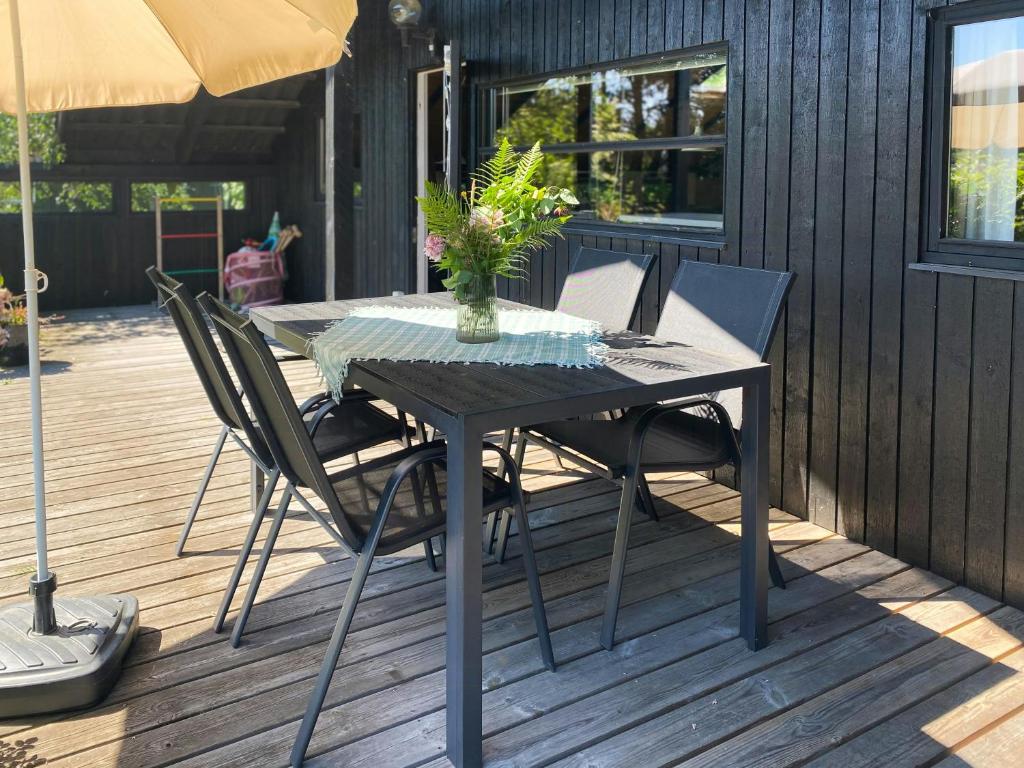 a table with chairs and a vase on a deck at Black Wooden Cottage Near Forest And Beach in Melby