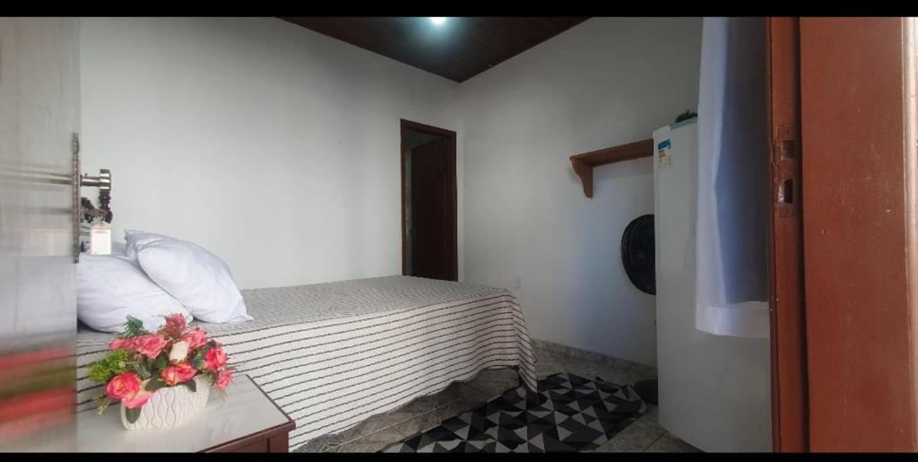 a small room with a bed and flowers on a table at Suites Praia Forte Dunas in Cabo Frio