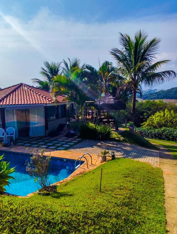 a house with a swimming pool and palm trees at Chalé Aconchegante em Piracaia in Piracaia