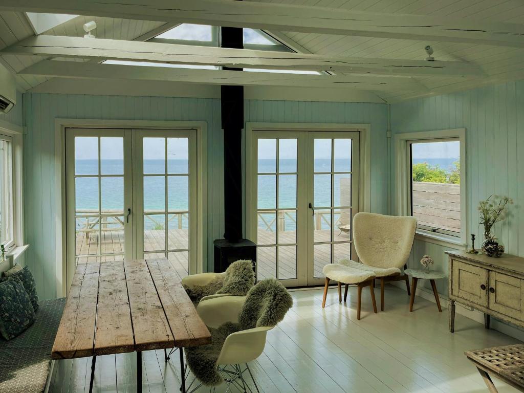 un salon avec une table et des chaises et l'océan dans l'établissement Cosy Holiday Home With Magical Views Near Vejby, à Vejby