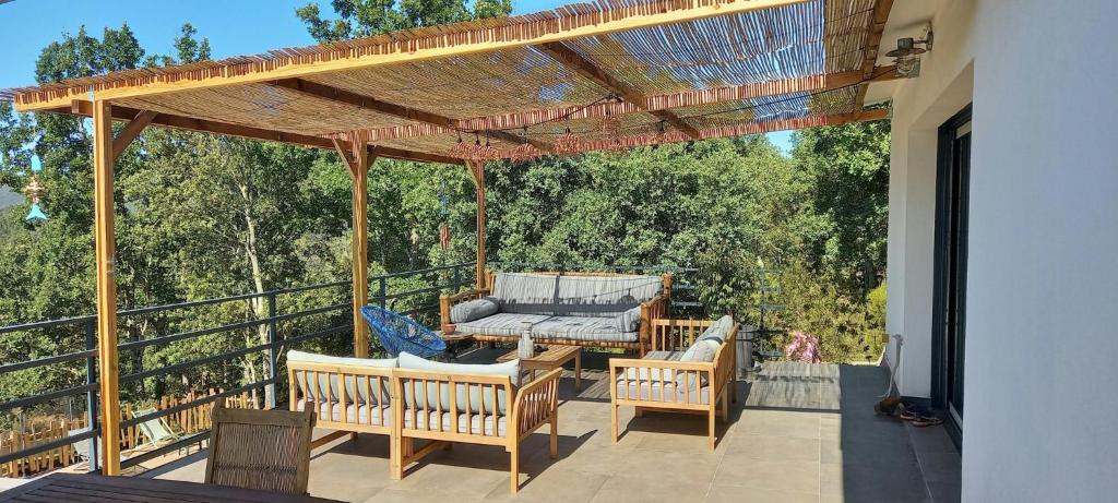 une pergola en bois avec des chaises et une table sur une terrasse dans l'établissement Villa Overlooking The Blavet Gorges, à Saint-Paul-en-Forêt