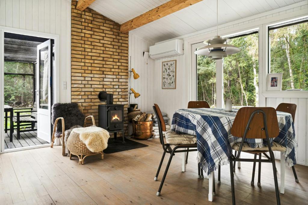 a dining room with a table and chairs and a fireplace at Forest Vibe And Idyll On Møn in Stege