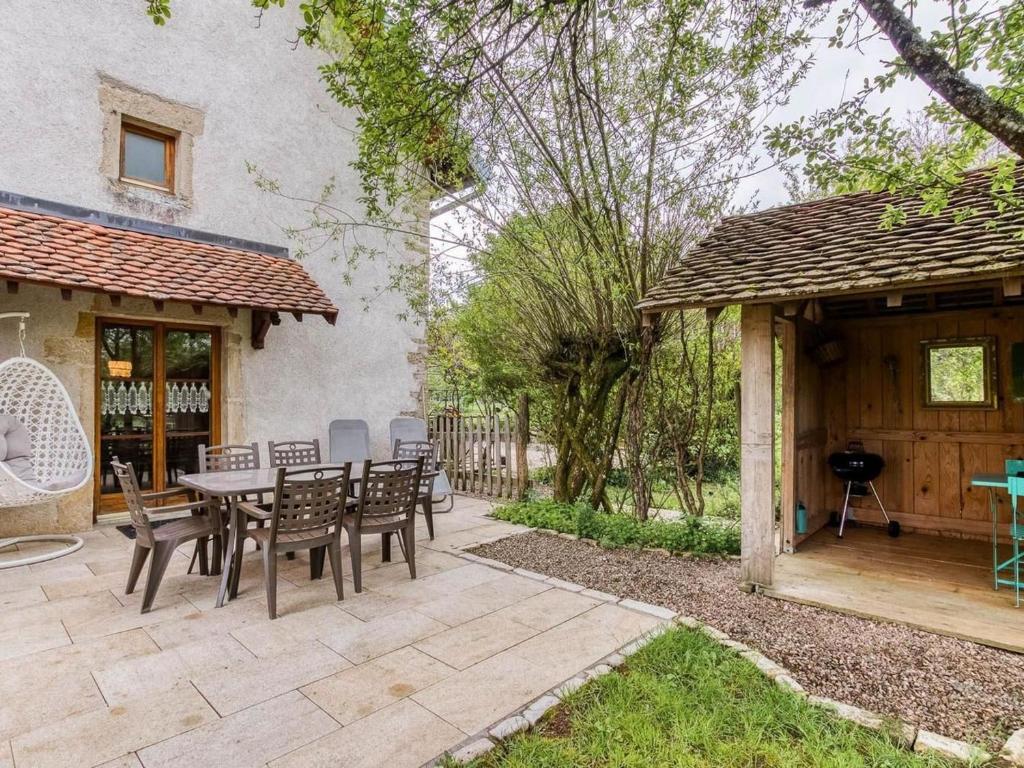 a patio with a table and chairs and a house at Gîte calme proche Villersexel, nature et activités - FR-1-583-450 in Esprels