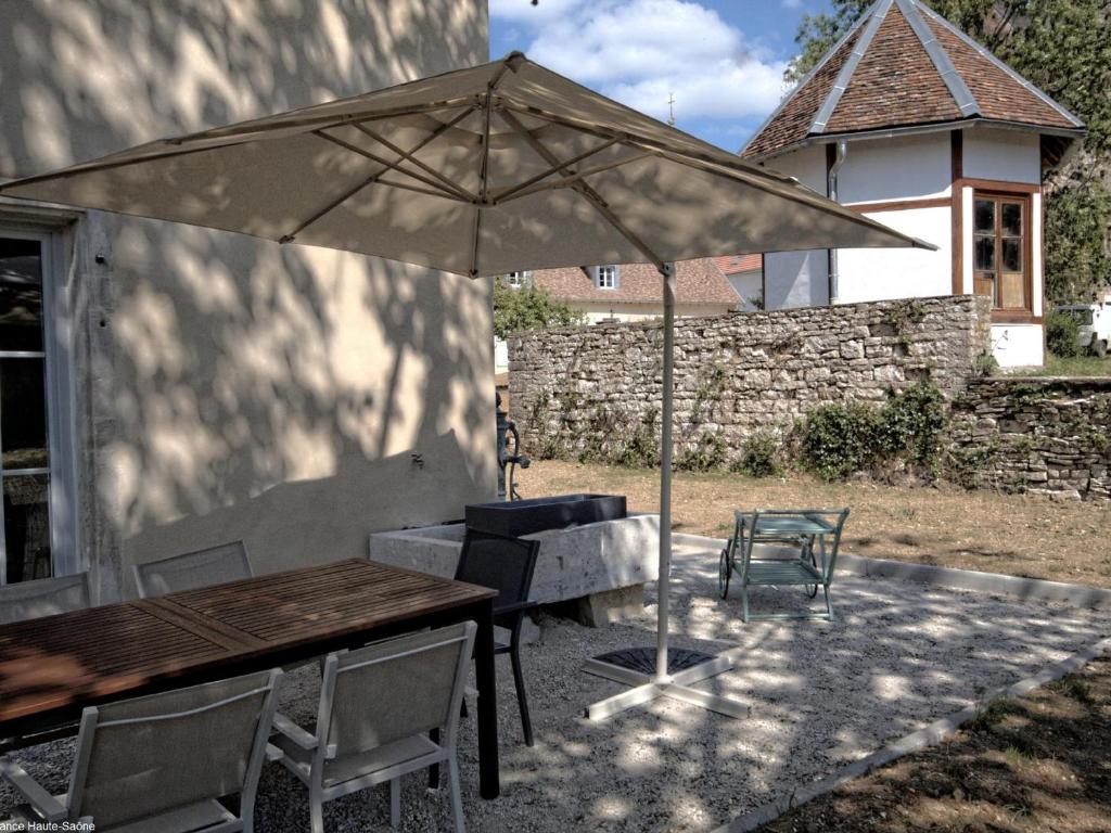 a table and an umbrella with a table and chairs at Charmant gîte rénové avec terrasse et parking au cœur de Montagney - FR-1-583-482 in Montagney